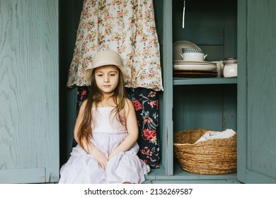 little cute Armenian girl sit in retro vintage wardrobe and playing hide-and-seek in country house and having fun, concept of simple life and spring