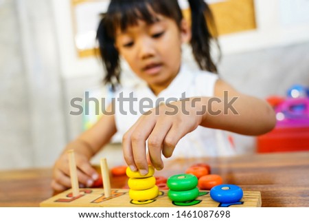 Little cute asian girls playing on the counting toy at kindergarten classroom. 