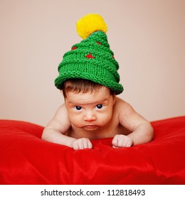 Little Cute Baby With Christmas Tree Hat On Red Background