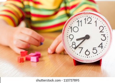 Little cute baby with clock at the table.