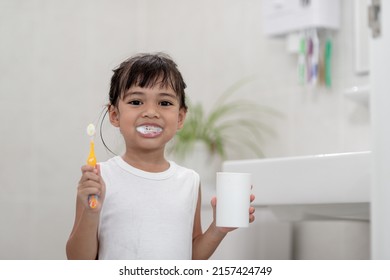 Little Cute Baby Girl Cleaning Her Teeth With A Toothbrush In The Bathroom