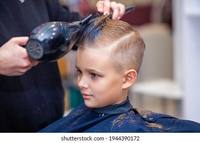 A little cute boy with blue hair sits in a hairdresser's at a stylist's, a schoolboy has his dyed hair dried with a hairdryer in a beauty salon, a child in a hairdresser's, a short men's haircut.
 - Powered by Shutterstock