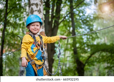 Little cute boy enjoying activity in a climbing adventure park on a summer sunny day. toddler climbing in a rope playground structure. Safe Climbing extreme sport with helmet and Carabiner. insurance - Powered by Shutterstock