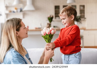 Little cute boy giving his mother tulips as a gift for Easter. Happy Mother`s Day! Small kid son giving present gift for birthday to his mom. Family time together - Powered by Shutterstock