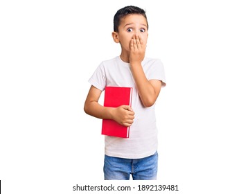 Little Cute Boy Kid Reading A Book Covering Mouth With Hand, Shocked And Afraid For Mistake. Surprised Expression 