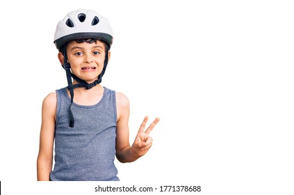 Little cute boy kid wearing bike helmet smiling with happy face winking at the camera doing victory sign. number two. 