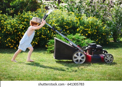 little cute boy mows lawn with mower