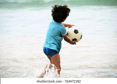 Little Cute Boy Playing Soccer Inside The Water