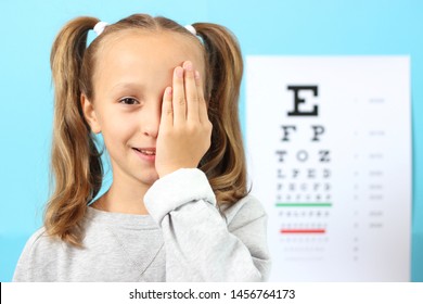 little cute cheerful girl passes an eye test in the office of an ophthalmologist
