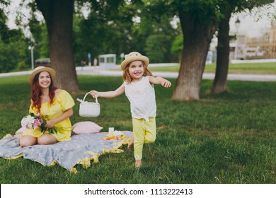 Little cute child baby girl with basket play and have fun, rest with woman in yellow clothes on green grass in park. Mother, little kid daughter. Mother's Day, love family, parenthood, childhood - Powered by Shutterstock