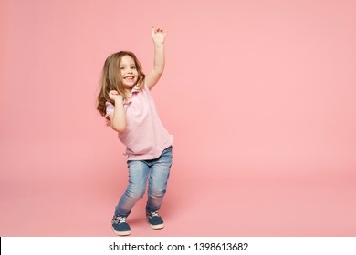 Little cute child kid baby girl 3-4 years old wearing light clothes dancing isolated on pastel pink wall background, children studio portrait. Mother's Day, love family, parenthood childhood concept