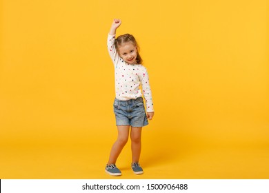 Little cute child kid baby girl 4-5 years old wearing light denim clothes isolated on pastel yellow wall background, children studio portrait. Mother's Day, love family, parenthood childhood concept