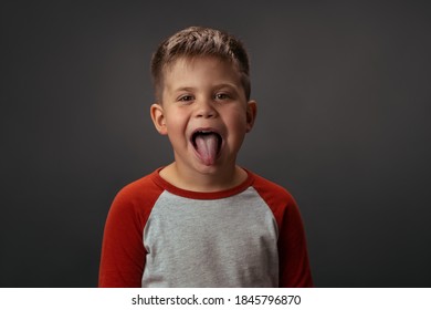 Little Cute Child. Shows His Tounge. Is Isolated On Grey Background. High Quality Photo