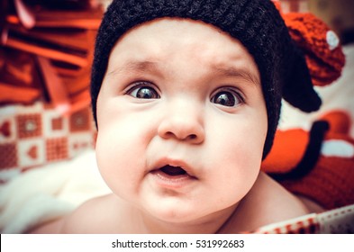 Little cute girl in black knitted hat looks at the world with their curious eyes.