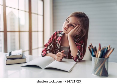Little cute girl is bored and tired with doing her homework. - Powered by Shutterstock