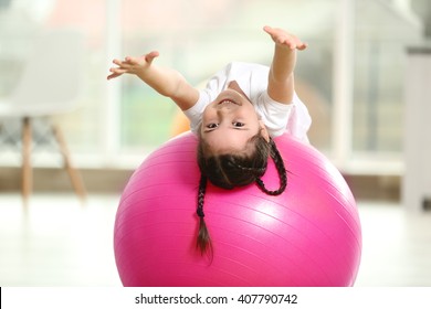 Little cute girl doing exercises with ball indoor