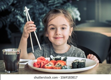 Little cute little girl eating sushi in a cafe, concept of eating
