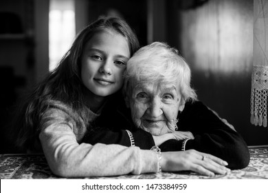 A Little Cute Girl Hugs Her Grandmother. Black And White Portrait.