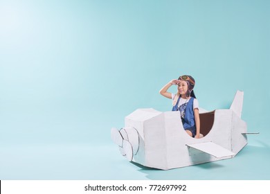 Little cute girl playing with a cardboard airplane. White retro style cardboard airplane on mint green background . Childhood dream imagination concept . - Shutterstock ID 772697992