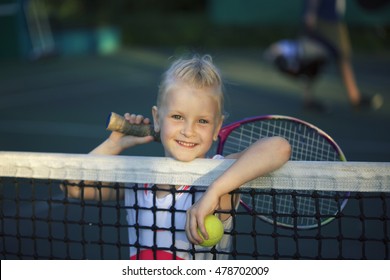 little cute girl playing tennis outside at the tennis court