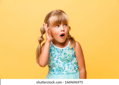 Little cute girl porrait isolated on yellow background. Blonde little baby with hands at mouth. Portrait of shocked little girl in blue dress isolated on yellow background . - Shutterstock ID 1469696975