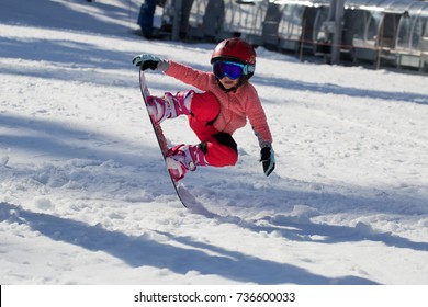 Little Cute Girl Snowboarding  making a tricks at ski resort in sunny winter day. Caucasus Mountains. Mount Hood Meadows Oregon 