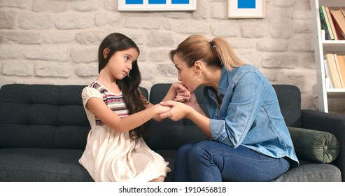 Little Cute Girl Talking To Her Mother Sitting On Sofa At Home. Loving Happy Mother, Sad Cute Kid Comforting Her Daughter, Making Her Laugh. Lifestyle At Home.