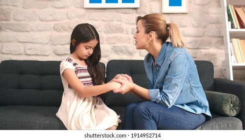 Little Cute Girl Talking To Her Mother Sitting On Sofa At Home. Loving Happy Mother, Sad Cute Kid Comforting Her Daughter, Making Her Laugh. Lifestyle At Home.