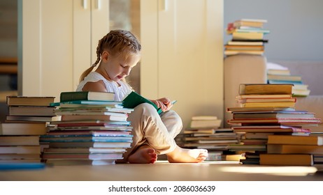 A little cute girl in a yellow dress reading a book sitting on the floor - Shutterstock ID 2086036639