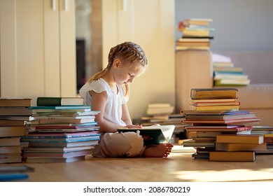 A little cute girl in a yellow dress reading a book sitting on the floor - Shutterstock ID 2086780219