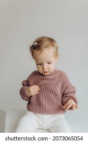 Little Cute Happy Baby Girl In A Pink Sweater And White Pants On A White Background. Smiling Child.