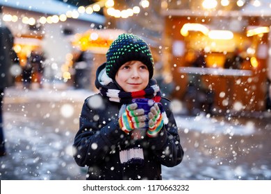 Little Cute Kid Boy Drinking Hot Children Punch Or Chocolate On German Christmas Market. Happy Child On Traditional Family Market In Germany, Laughing Boy In Colorful Winter Clothes