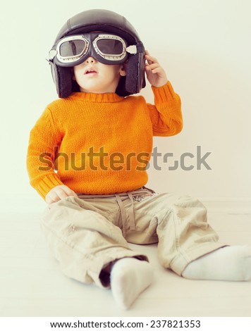 Little cute playful baby kid with pilot hat and goggles ready for airplane flying