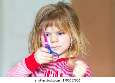 Little Cute Toddler Girl Making Experiment With Scissors And Cutting Hairs. Funny Baby Child Cuts Her Pony Herself At Home. Trouble.