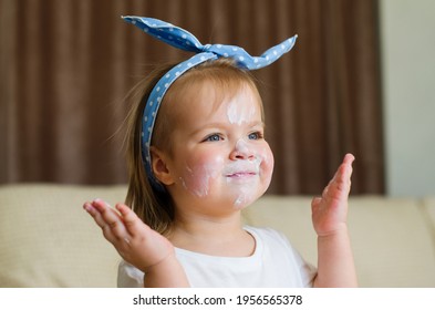 Little Cute Two Years Old Girl With Face Cream On Her Cheeks, Nose And Forehead. Toddler Testing The Mother's Cream At Home. Child Skin Protection, Organic Cream, Health And Skin Care