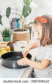 Little Dark-haired Girl 3 Years Old In Red Headband Bakes Apple Pie In Kitchen. Child Oils Baking Dish. Children Help On Household Chores. Kid Cooking Food. Vertical