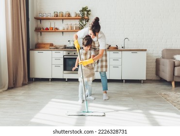 a little daughter and her mom clean the house, a child washes the kitchen floor, a cute little helper girl cleans the floor with a mop, a happy family cleans the room. - Powered by Shutterstock