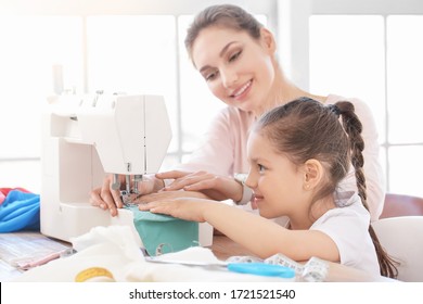 Little daughter with her mother sewing protective masks at home