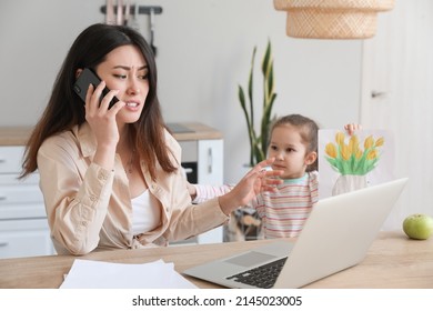 Little daughter keeping mother from her work at home - Shutterstock ID 2145023005