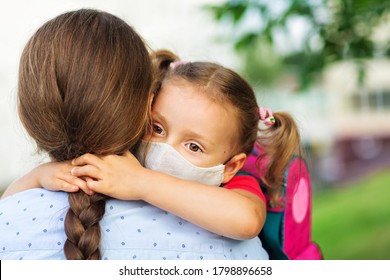 A Little Daughter In Medical Mask Hugs Her Mother Before School . Concept Of Care, Education And Health.