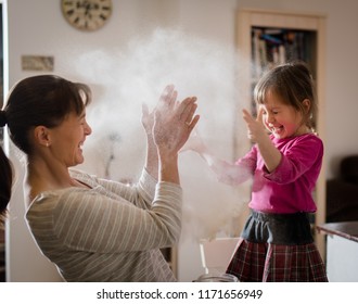 Little Daughter With Mother Throwing Flour And Having Fun By Baking