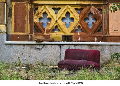 A Little And Dirty Red Love Seat On The Grass Of The Garden Of An Abandoned Villa Of Nineteenth Century In Italy