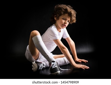 Little disappointed boy soccer player sitting on the floor with untied lace on the boot. Dark background - Powered by Shutterstock