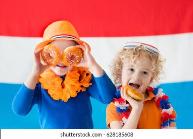 Little Dutch Boy And Girl Wearing Country Symbols Eating Orange Donuts Celebrating King Day. Children Support Holland Sport Team. Kids From The Netherlands. Young Sport Fans With National Flag