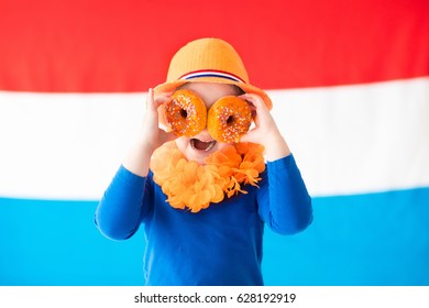 Little Dutch Boy Girl Wearing Country Symbols Eating Orange Donuts Celebrating King Day. Children Support Holland Sport Team. Kids From The Netherlands. Young Sport Fans With National Flag