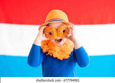 Little Dutch Boy Girl Wearing Country Symbols Eating Orange Donuts Celebrating King Day. Children Support Holland Sport Team. Kids From The Netherlands. Young Sport Fans With National Flag.