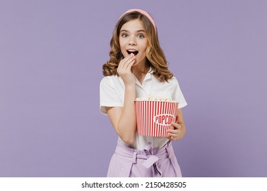 Little excited amazed surprised kid girl 12-13 years old in white shirt hold plastic takeaway popcorn bucket watch movie film isolated on purple background studio Childhood children lifestyle concept - Shutterstock ID 2150428505