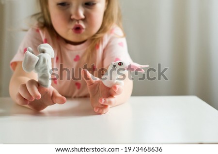 Little expressive girl playing theater with animal finger puppets. Role-playing games and activities have the potential to improve language
skills, creativity, social awareness, emotional development