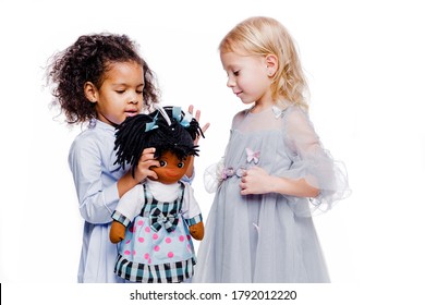 Little fashionable girls are friends of two different nationalities. African American girl showing doll to her friend