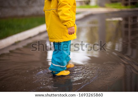 Similar – Image, Stock Photo Small infant boy wearing yellow rubber boots and yellow waterproof raincoat standing in puddle on a overcast rainy day. Child in the rain.